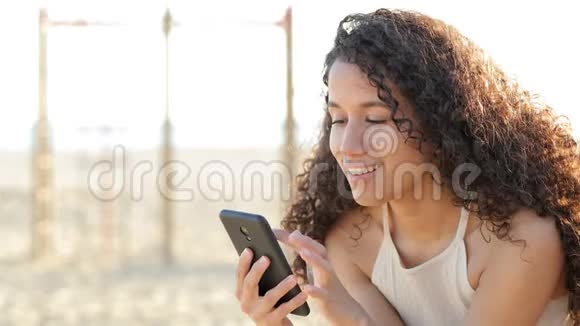 快乐的拉丁女人在海滩上用智能手机视频的预览图
