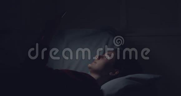 年轻女性在智能手机上联网晚上躺在床上视频的预览图