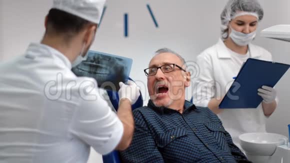 男性牙科医生对成熟患者进行口腔X光检查中型摄影机视频的预览图