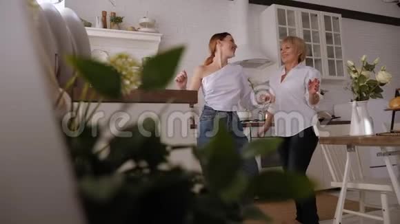一位年迈的母亲和一个成年的女儿在厨房里跳舞在家里玩得开心视频的预览图