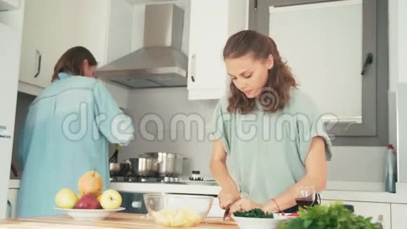 两个年轻漂亮的女人在明亮的厨房里唱歌跳舞视频的预览图