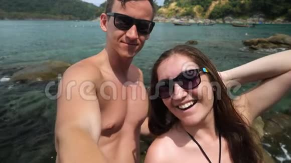 戴太阳镜的快乐情侣在海边自拍视频的预览图
