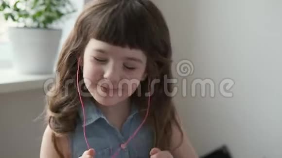 女孩用粉色耳机和舞蹈听音乐视频的预览图