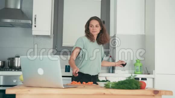 年轻女子在厨房做饭同时通过互联网与朋友交谈视频的预览图