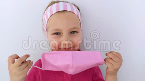 戴着头巾的小女孩戴着防冠状病毒的粉色防护面具戴着白色的检疫背景视频的预览图