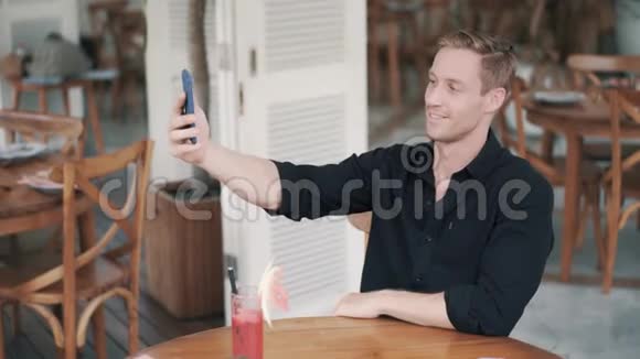 帅哥的肖像在咖啡馆打电话自拍微笑显示和平标志视频的预览图