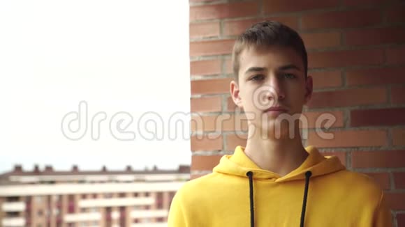 穿着黄色运动衫的青少年在一条城市街道的砖墙附近戴上了一个面部医疗面具视频的预览图
