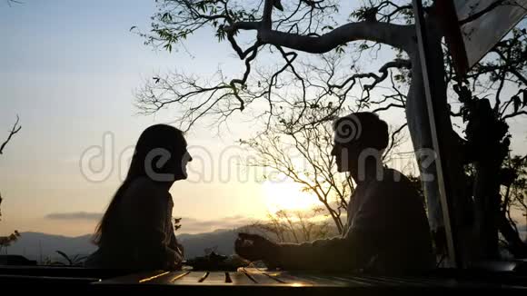 一对年轻夫妇在美丽的夕阳背景下的咖啡馆里视频的预览图