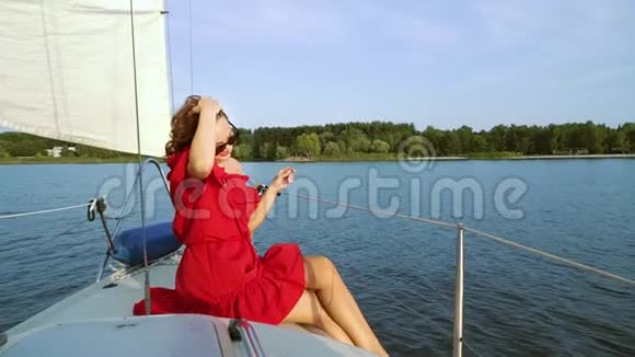 穿着红裙子享受帆船度假的漂亮女人视频的预览图