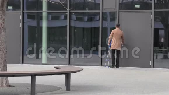 商务中心里一个穿着米色外套拄着拐杖的商人视频的预览图