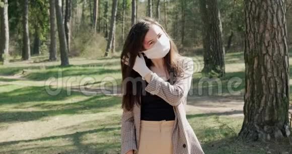 一位年轻女子在针叶林中戴上防护面具的肖像保护covid19冠状病毒病毒视频的预览图