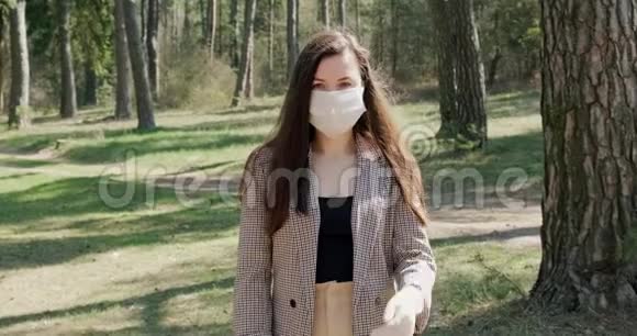 针叶林中戴防护面具的年轻女子的肖像保护covid19冠状病毒病毒视频的预览图