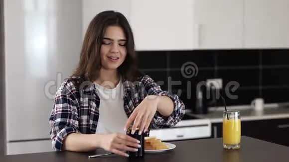 检疫期间厨房里的年轻女子坐在桌子旁在烤面包上放些果酱早上吃美味的早餐视频的预览图