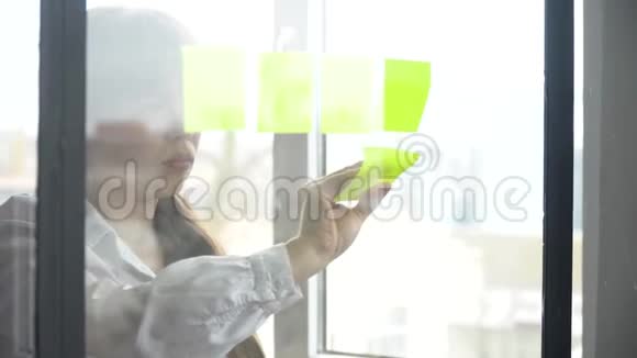 商务女性使用粘性笔记解决策略玻璃白板视频的预览图