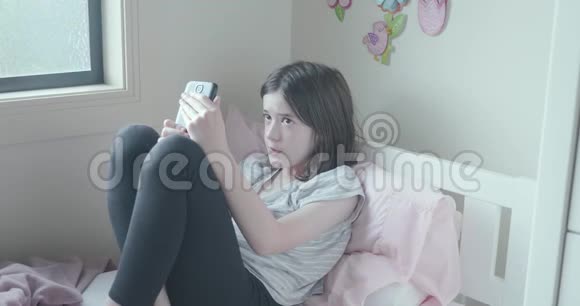 年轻女孩用手机从床上掉下来微笑着视频的预览图