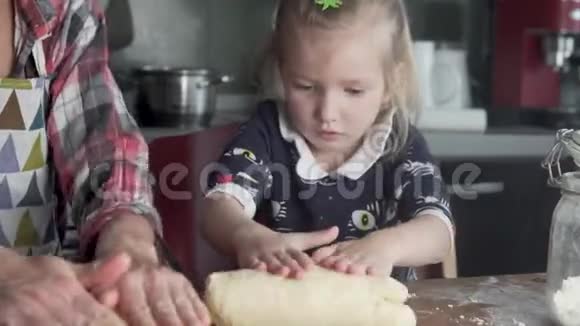 妈妈和小女儿在家里的厨房里准备蛋糕面团视频的预览图