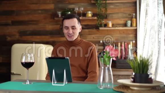 年轻人在网上交流时在平板电脑前举起一杯葡萄酒视频的预览图