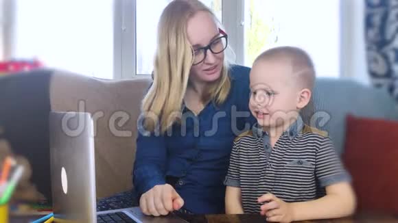 学龄前儿童从事家庭教育这个男孩坐在一张桌子旁在网上写作画画和学习检疫到期视频的预览图