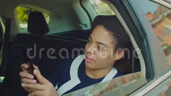 可爱的女人在车后座上打电话视频的预览图