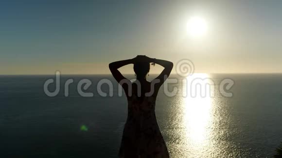 在日落时分穿着夏装的女人在沙滩上举手视频的预览图