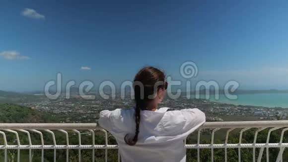 年轻女子穿着白色上衣举手欣赏风景视频的预览图
