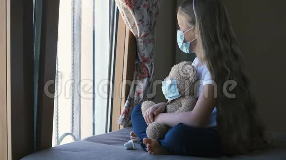 呆在家里检疫冠状病毒大流行预防伤心的女孩和他的玩具熊都戴着防护口罩视频的预览图