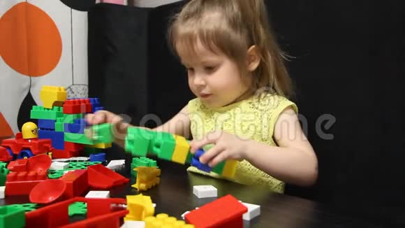 三岁的女孩在玩一个建设者的彩色积木孩子培养自己的思维能力发展和发展视频的预览图