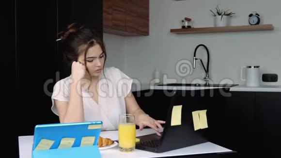 检疫期间厨房里的年轻女子在家远程工作使用笔记本电脑开始快乐快乐和视频的预览图