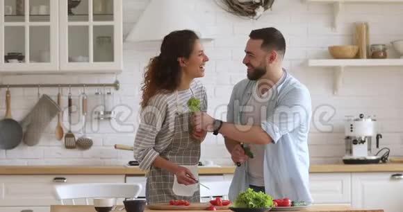 快乐的年轻夫妇喜欢一起做饭一起开厨房玩笑视频的预览图