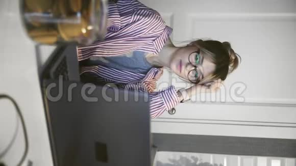 年轻女子在厨房用笔记本电脑工作的垂直视频视频的预览图
