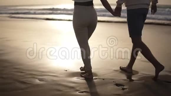 轻松的一对夫妇赤脚在海滩上散步他们在空的平静的海岸上共度时光年轻人视频的预览图