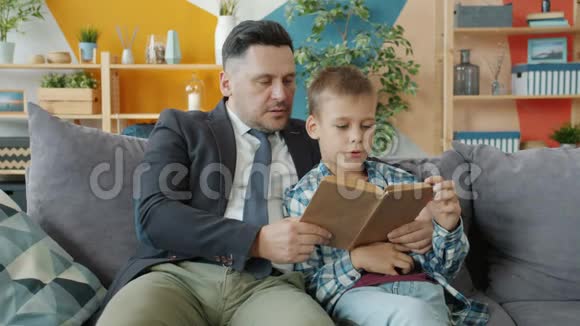 父亲在公寓里给快乐的小男孩读正式服装书视频的预览图