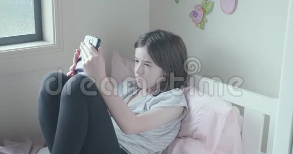 年轻女孩在床上用手机专心致志视频的预览图