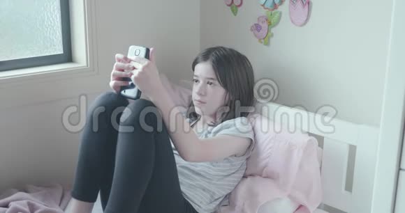 一个年轻女孩在床上独自使用手机视频的预览图