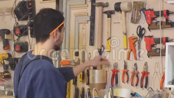 穿制服的年轻木匠挑选适合做木工的工具视频的预览图