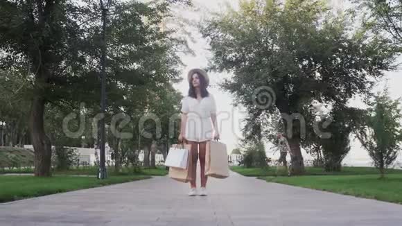 带着购物袋的年轻女人在夏天的公园里等她的男朋友视频的预览图