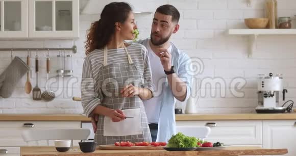 快乐有趣的年轻夫妇在厨房准备沙拉的时候开玩笑视频的预览图