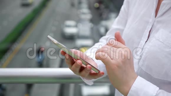 女士双手握着智能手机在桥上打字视频的预览图