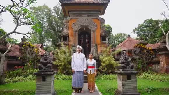 印尼当地巴厘岛夫妇穿着传统服装微笑着拍照视频的预览图