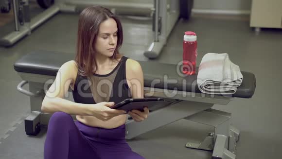 健身青年妇女在健身房训练后休息时从瓶子里喝水视频的预览图