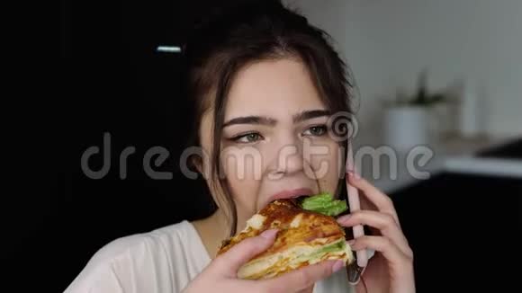 检疫期间厨房里的年轻女子女孩在智能手机上聊天吃美味可口的三明治吃早餐吧视频的预览图