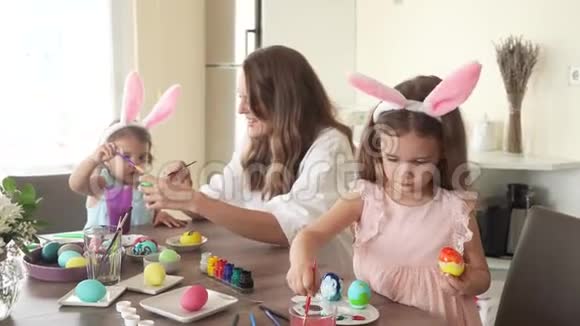 准备复活节的幸福家庭妈妈和女儿一起用有趣的兔子耳朵画复活节彩蛋4K视频的预览图