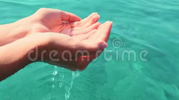 两只雌性双手捧着晶莹剔透的海水杯状手中的特写镜头视频的预览图