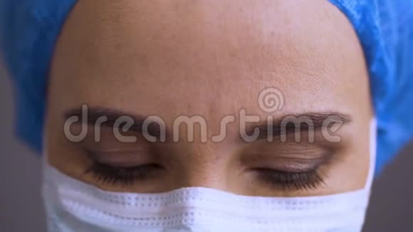 关闭戴面具的女医生向下看然后看着科维德19病人心烦意乱医生眼睛搜索信息视频的预览图