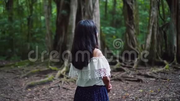 美丽的亚洲女孩在惊人的丛林森林转身并看镜头视频的预览图