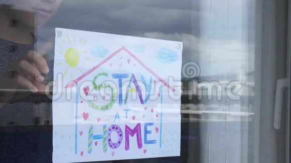 孩子在家贴着窗玻璃画着刻字的画呆在家里社会媒体运动视频的预览图