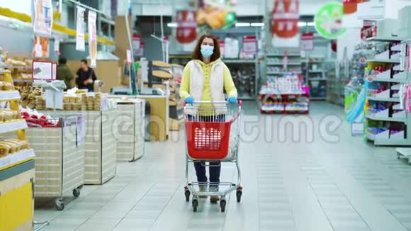 家庭主妇戴着医用口罩和手套在超市购物视频的预览图