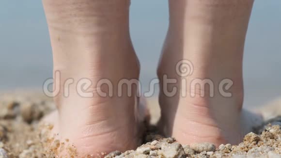 一个人的特写他的脚在海滩上走进水里背面视频的预览图