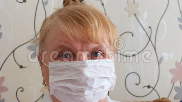 一位戴着医疗面具的老年妇女在隔离和自我隔离中保护老年人免受病毒和疾病的侵害视频的预览图