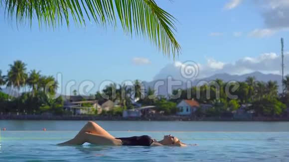 一位年轻女士在热带度假胜地放松这里有温泉瀑布和游泳池还有热水视频的预览图